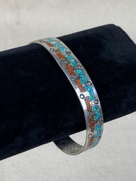 Native American Sterling Silver Cuff Bracelet with Turquoise and Coral: Sterling silver cuff bracelet featuring turquoise and coral inlay. Native American maker's mark stamped on the interior of the cuff. Measures approximately 2 1/2" in diameter. In good condition with l