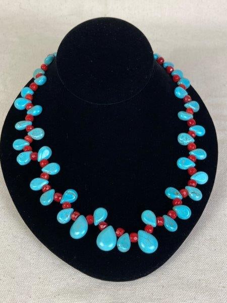 Southwestern-Style Turquoise and Coral Necklace: A Southwestern-style necklace featuring teardrop-shaped turquoise stones and multifaceted coral beads arranged intermittently along the strand, completed with a silvertone magnetic clasp. The necklace