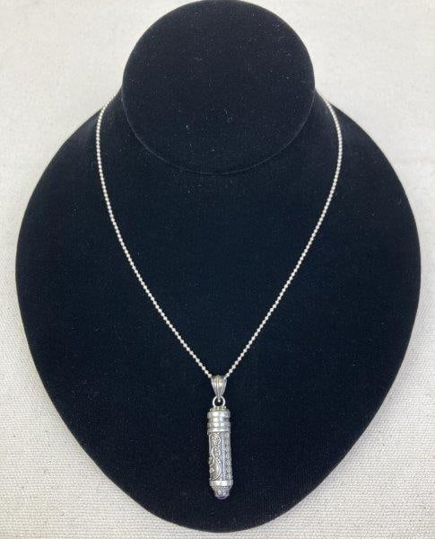 Sterling Silver Snuff Urn Necklace: Sterling silver snuff urn pendant adorned with delicate scrollwork and floral motifs, finished with an amethyst cabochon at the base. Suspended from a sturdy sterling ball chain with a clasp stamped 9