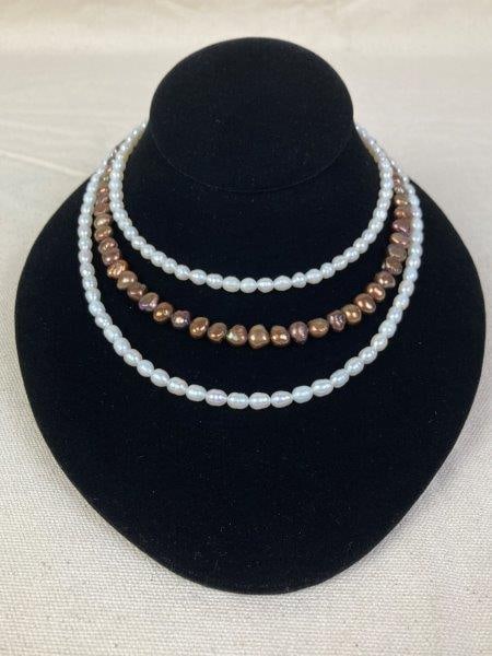 Three Cultured Pearl Necklaces: Comprising three stringed cultured pearl necklaces, including two strands of white pearls and one strand of brown pearls with iridescent hues. Unmarked. Longest measures approximately 18" long. In goo
