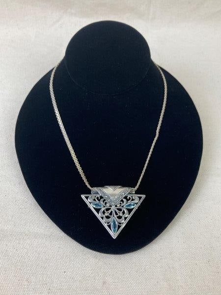 Sterling Silver Necklace with Filigree Pendant Brooch: Elegant sterling silver necklace featuring a detachable filigree pendant brooch set with a prominent blue gemstone resembling blue topaz, accented by smaller clear stones. Both chain and pendant are m
