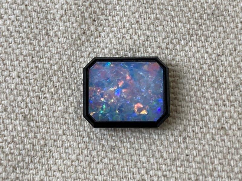 Opal Doublet: Opal doublet featuring a vibrant play of color, with the opal bonded to a dark backing to enhance its iridescence. Measures approximately 9/16" high x 1" wide. In good condition