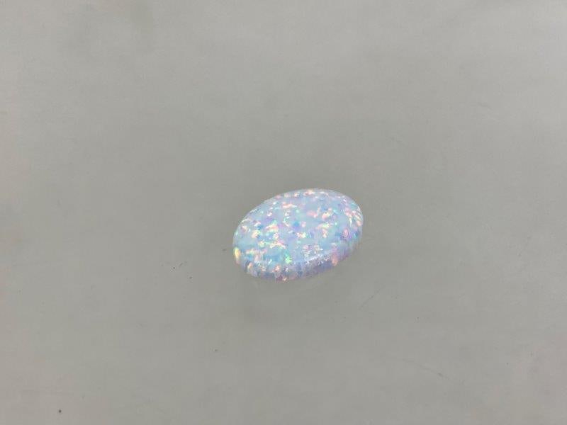 Oval Opal Gemstone: A captivating semi-precious oval opal gemstone celebrated for its vivid play of color, displaying shifting hues and patterns when viewed under light. Measures approximately 5/8 inch. In good condition