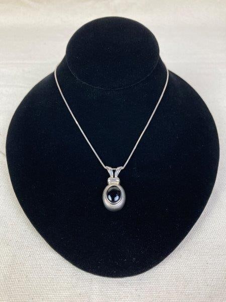 Sterling Silver Necklace with Black Onyx Pendant: Elegant sterling silver necklace featuring a polished black onyx pendant suspended from a classic box chain. Pendant stamped 925. Chain measures approximately 18" long with a 1 1/4" drop. In good cond