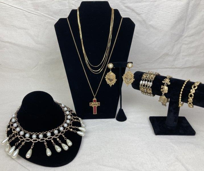 Collection of Gold-Tone Jewelry Including Trifari Necklace: Collection of gold-tone jewelry comprising necklaces, bracelets, and earrings. Designs include dangling teardrop-shaped faux pearls, a cross with red enamel, and additional decorative motifs. One neck