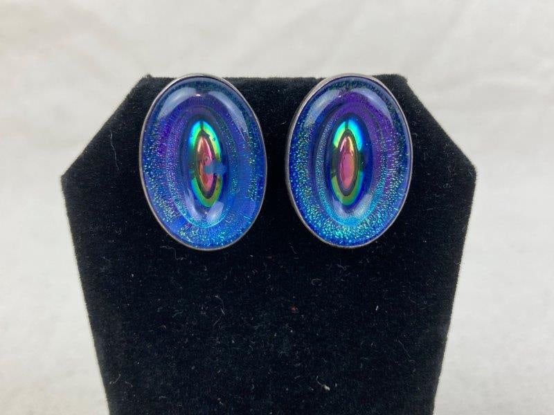 Pair of Sterling Silver and Dichroic Glass Earrings: Pair of oval dichroic glass stud earrings encased in sterling silver, displaying vibrant iridescent tones that shift with the light. Stamped STERLING on the reverse and measuring approximately 1" long