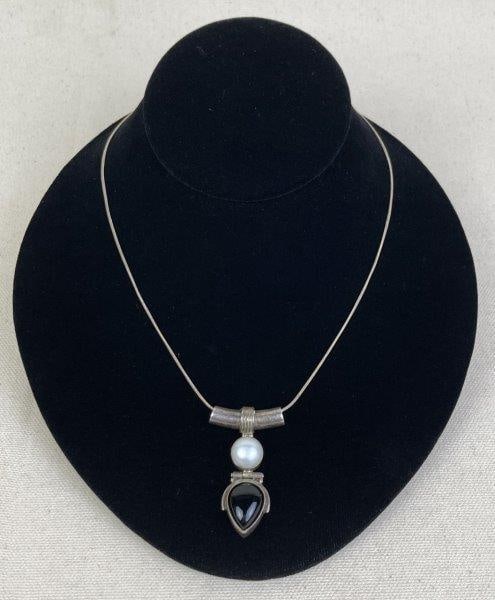 Sterling Silver Necklace with Black Onyx and Faux Pearl Pendant: Artisan-crafted sterling silver necklace featuring a modernist-style pendant set with a polished black onyx and a luminous faux pearl, creating a striking contrast of tone and texture. Pendant stamped