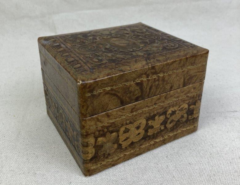 Embossed Leather Box with Gilt Coat of Arms Design: Elegant embossed leather box featuring gilt details and a central coat of arms design on the lid. Measures approximately 3'' H x 4 1/2'' W x 3 3/4'' D. Good condition with light wear consistent with a