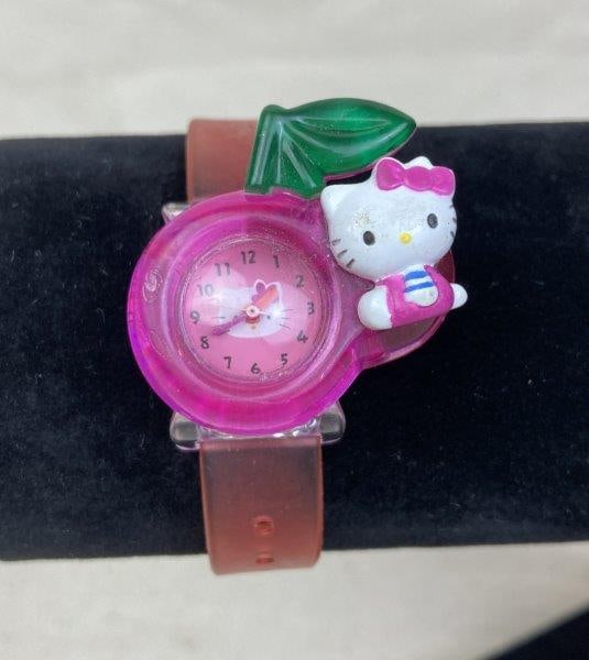 Hello Kitty Sanrio Youth Watch: Playful Hello Kitty youth wristwatch featuring the iconic kitty logo on the dial and a flexible rubber band with adjustable sizing for comfort. In good condition with light wear consistent with age an