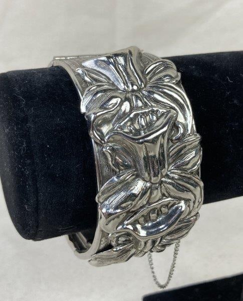 Art Nouveau-Style Bangle Bracelet with Daffodil Motif: Elegant Art Nouveau-style bangle bracelet featuring raised relief daffodil designs encircling the band, highlighting the era's signature organic and floral detailing. Measures approximately 2 1/2" in