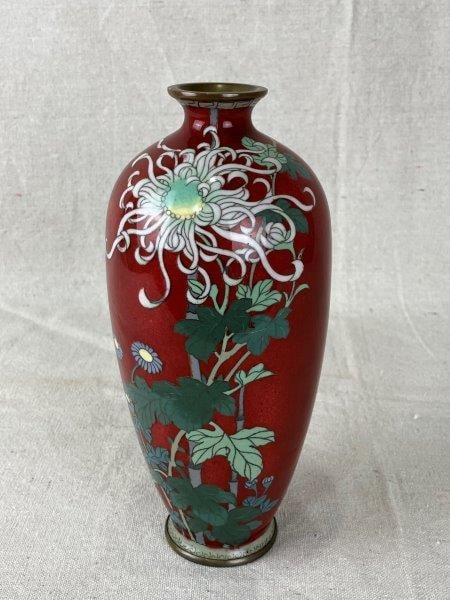 Japanese Cloisonné Vase: Elegant cloisonné vase featuring brilliantly executed enamel decoration on a rich red curving form. A fine example of Japanese artistry and craftsmanship. Measures approximately 8 3/4" H x 3" in 