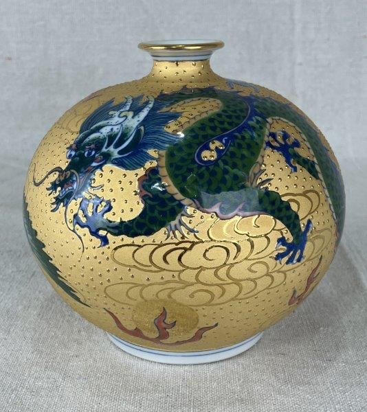 Japanese Kutani Kozan Dragon Vase: Handsome vase decorated with a dynamic dragon and phoenix motif set against a shimmering gold-enameled surface. Kutani Kozan mark on base. Measures approximately 5 3/4" H x 5" in diameter. Impressed s