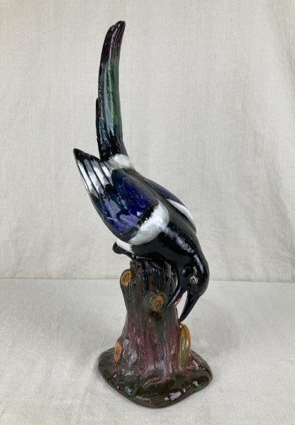 High Quality Porcelain Magpie: Vibrant porcelain figure of a magpie perched on a naturalistic stump, finely hand-painted with lifelike detail. The stump features an added detail of a slug. Measures approximately 18" H x 4 3/4" W x 