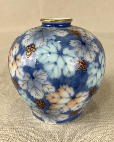 Japanese Fukagawa Porcelain Vase: Elegant Fukagawa porcelain vase decorated in a rich blue palette accented with gold and brilliant red-orange tones, featuring a leaf and grape motif in fine detail. Measures approximately 3 3/4" H x 3
