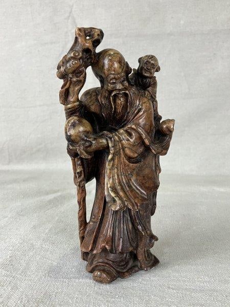 Chinese Carved Stone Figure of Shou Lao: Finely carved stone figure depicting Shou Lao, the Chinese God of Longevity, rendered with traditional iconographic attributes and intricate surface detailing.Measures approximately 7 1/8" H x 3 1/8"