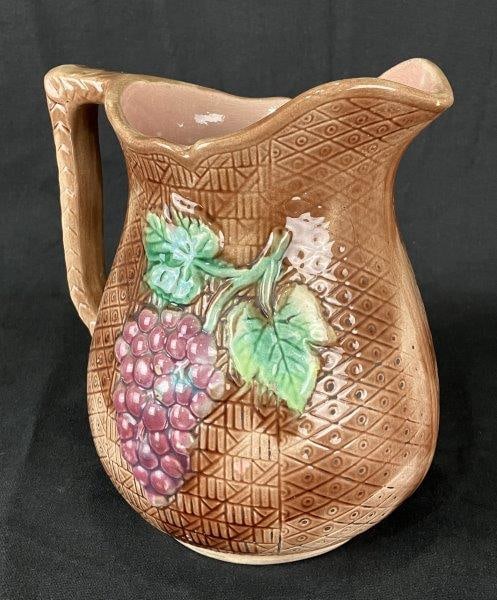 Majolica Pitcher with Fruit Motifs: Charming majolica pitcher featuring sculptural fruit motifs of grapes and apples against a richly textured brown ground, with an applied handle. A fine decorative example of majolica ware. Measures ap