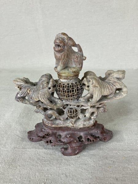 Chinese Soapstone Carving: Richly carved soapstone sculpture featuring an intricate depiction of dogs, executed with fine detail and craftsmanship typical of Chinese decorative arts. Measures approximately 6 5/8" H x 6 3/4" W x