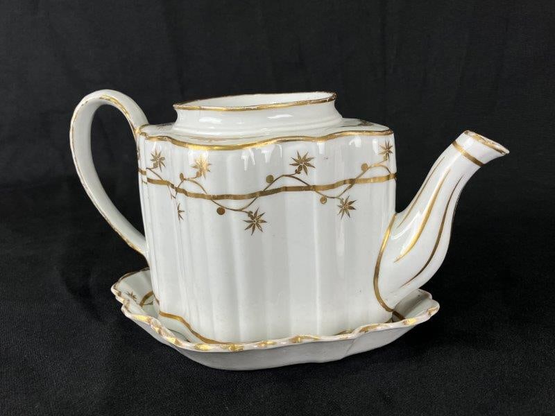 Early Decorated Teapot with Underplate: Charming early teapot and underplate featuring interlocking floral decoration and an elegant fluted form. The teapot measures approximately 5" H x 9 1/2" W x 5" D. Wear to gilded decoration, minor bas
