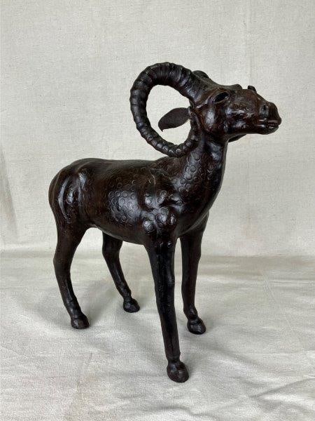 Leather-Embellished Ram Sculpture: Distinctive sculpture of a ram, embellished with intricate surface patterning and expressive features, finished in a deep brown tone for visual impact. Measures approximately 18" H x 16" W x 7 3/8" D 