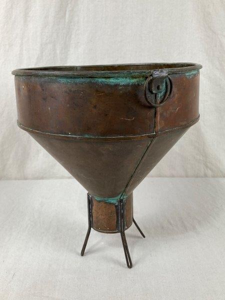 Early Copper Funnel: Early copper funnel with four legs and a side handle, displaying a rich aged patina. Measures approximately 13 3/4" H x 12 1/4" W x 11 3/4" D, Shows age-appropriate wear with some oxidation.