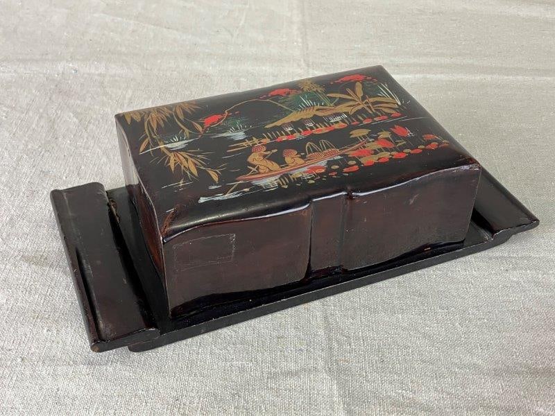 Japanese Lacquered Box: Intricately hand-painted Japanese lacquered box, decorated with charming figures set within a scenic landscape. A fine example of traditional lacquer artistry with rich surface detail and decorative a
