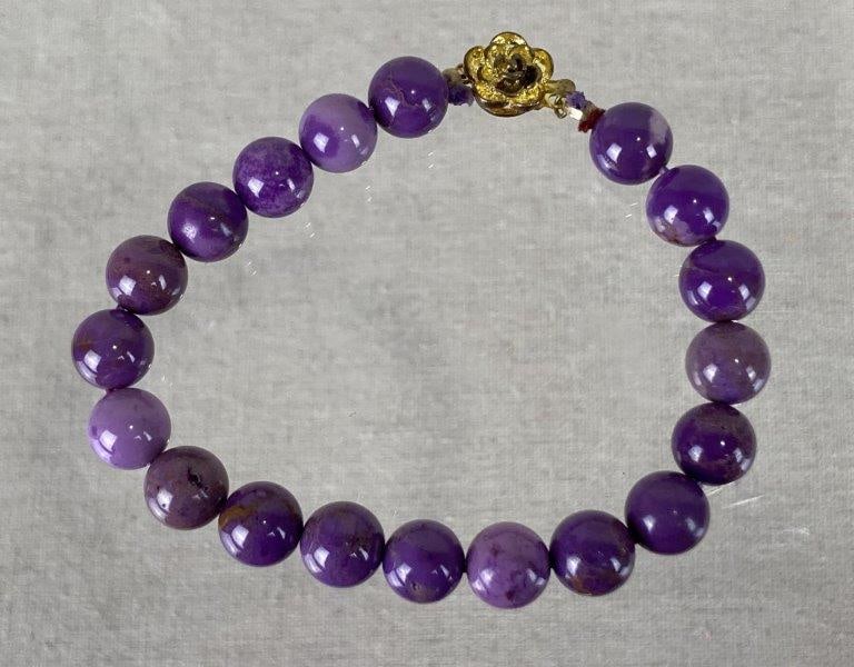 Phosphosiderite Bead Bracelet with Gold-Tone Clasp: Elegant bracelet composed of polished round phosphosiderite beads displaying a rich, soft purple hue, finished with a decorative gold-tone rose clasp. Measures approximately 7" long. In good condition