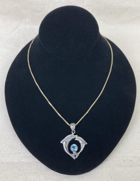 Sterling Silver and Blue Topaz Dolphin Motif Necklace: Charming sterling silver necklace featuring leaping dolphins intertwined with ornate filigree patterns, centered by a round brilliant-cut blue topaz stone. A delicate blend of oceanic inspiration and