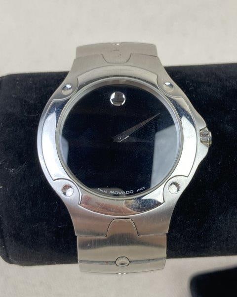 Movado Stainless Steel Watch: Elegant Movado Sports Edition stainless steel wristwatch featuring a black dial beneath a sapphire crystal and a link band with circular accent connectors. Swiss made and stamped Stainless Steel. Meas