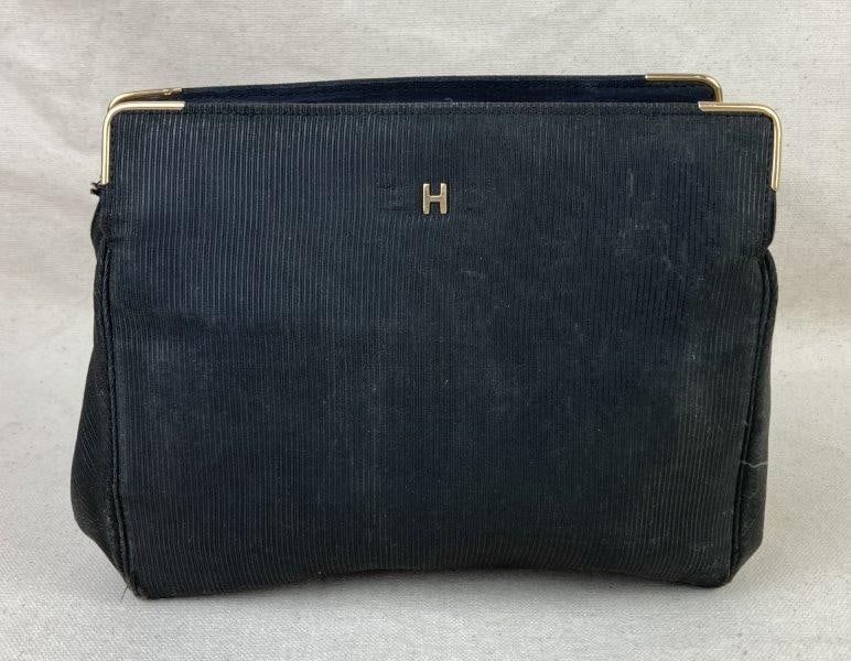 Vintage Black Clutch Purse: Chic vintage black clutch purse featuring a gold-tone "H" emblem on the face with coordinating gold metal accents along the clasp and top edge. The bag displays a linear textured exterior and black sa