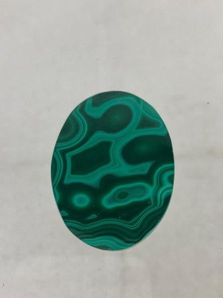 Oval Cut Malachite Cabochon: Beautiful oval malachite cabochon showcasing rich, variegated green banding and a high-polish finish that accentuates its natural patterning. A robust, well-proportioned stone measuring approximately