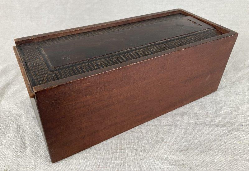 Inlaid Greek Key Mahogany Box: Rectangular wooden box with a sliding lid inlaid with a wood greek key design with alternating dark and light woods. Measures approximately 4 3/4" H x 12 1/8" W x 5 1/8" D. Small areas of wood loss.