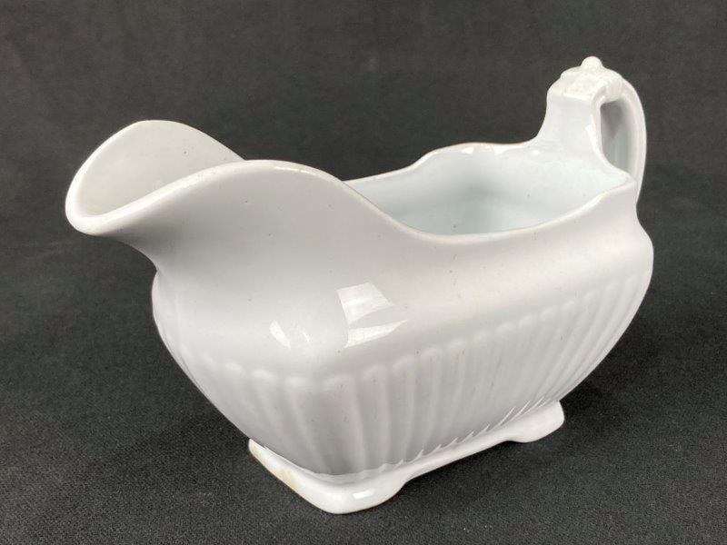 Ironstone Gravy Boat: Elegant ironstone gravy boat featuring a raised ribbed design, footed base, and curved handle. Stamped and made by Powell & Bishop. Measures approximately 4 3/8'' H x 3'' W x 7 1/2'' D. Good condition