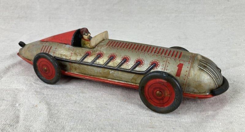 Schylling Tin Toy Spiral Race Car, Mid-20th Century: Lithographed tin race car with printed “Continental Record” wheels and seated driver figure. Measures approx. 3'' H × 12 1/4'' W × 3 7/8'' D. Spotting and age-related wear throug