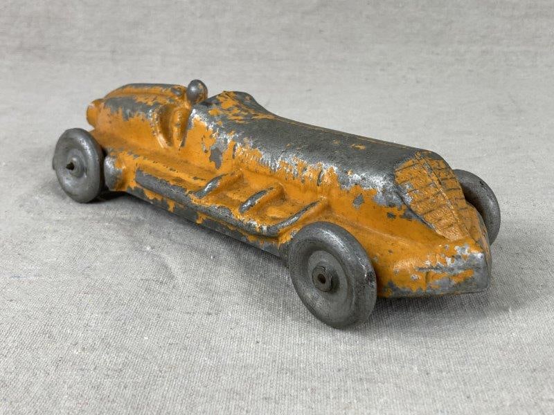 Cast Iron Vintage Toy Car: Early to Mid-20th Century, Cast iron toy car with elongated streamlined form and light orange paint. Measures approx. 3 in. H × 10 1/4 in. W × 3 3/8 in. D. Wear to paint with areas of expose