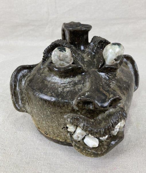 Southern Face Jug by Steve Abee: Expressive Southern face jug by North Carolina potter Steve Abee, featuring applied facial features with finely incised details and a dark alkaline glaze. Includes an applied handle and is signed R