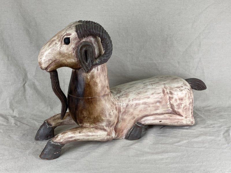 Polychrome Carved Goat: Life-sized polychrome carved goat showcasing expressive features and remarkable craftsmanship. The detailed carving highlights the artisan's skill, with finely rendered wood surface and lifelike propo