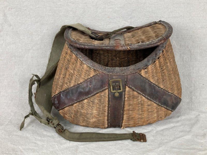 Woven Creel Basket: Classic woven creel basket featuring a combination of leather and wicker construction with a canvas carrying strap. Traditionally used for fishing, this example displays both function and rustic charm