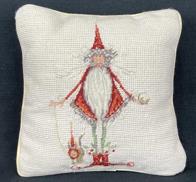 Needlework Santa Pillow: Charming pillow featuring a needlepoint Santa figure surrounded by a festive white patterned border. Rich in texture and holiday appeal. Measures approximately 9" H x 8" W x 2 1/2" D. Condition: Minim