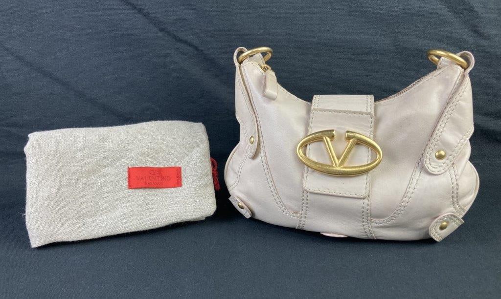 Valentino Catch Leather Hobo Bag: Valentino Catch leather hobo bag in soft cream tones, featuring a gold-tone V logo adornment and a sleek baguette-style silhouette that captures the house’s understated elegance. The interior is