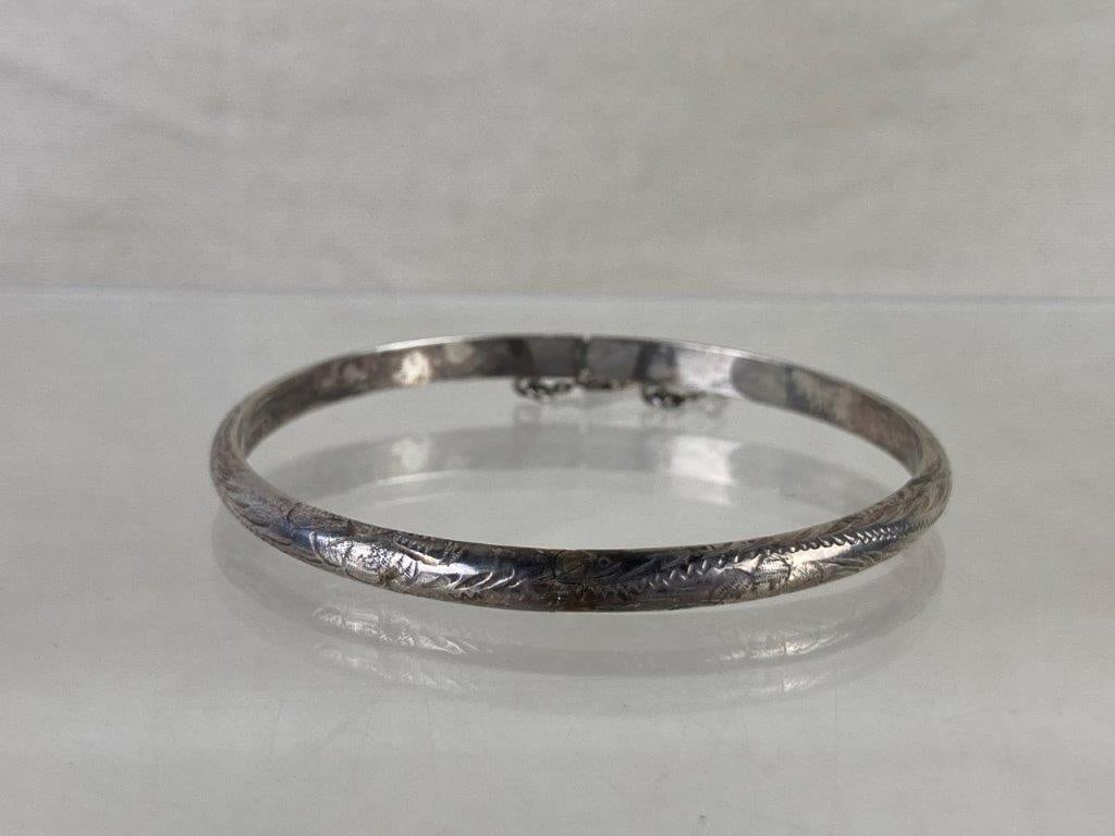 Sterling Silver Bangle: Sterling silver bangle featuring an elegant, artisan-crafted form with fine chased silverwork adding subtle texture and traditional detailing. Inner diameter measures approx. 2 3/8". Total weight 5.75