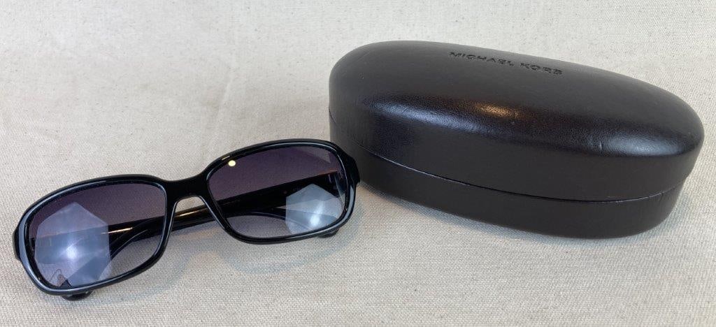 Michael Kors “Jardines” Sunglasses: Pair of women’s Michael Kors black sunglasses in the Jardines model, featuring sleek black frames with the signature MK logo in polished metal inlaid on the outer temples. Marked with serial num