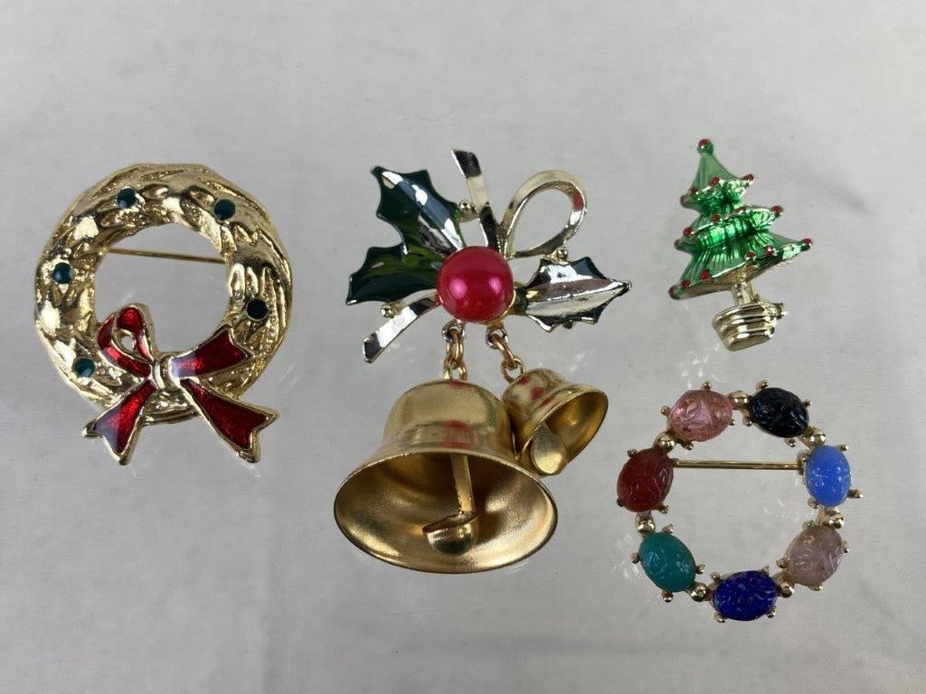 Four Christmas Brooches: Festive assortment of four Christmas-themed brooches including one wreath adorned with multicolored scarab-style forms, one gold tone wreath with enamel accents, one bell brooch decorated with holiday