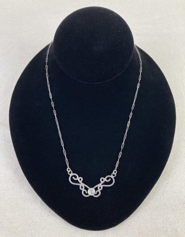 Artisan Sterling Silver and Moonstone Necklace: Artisan-crafted sterling silver necklace featuring an elegant scrollwork pattern surrounding a central cabochon moonstone that displays soft, ethereal glow characteristic of the stone. Paired with a d