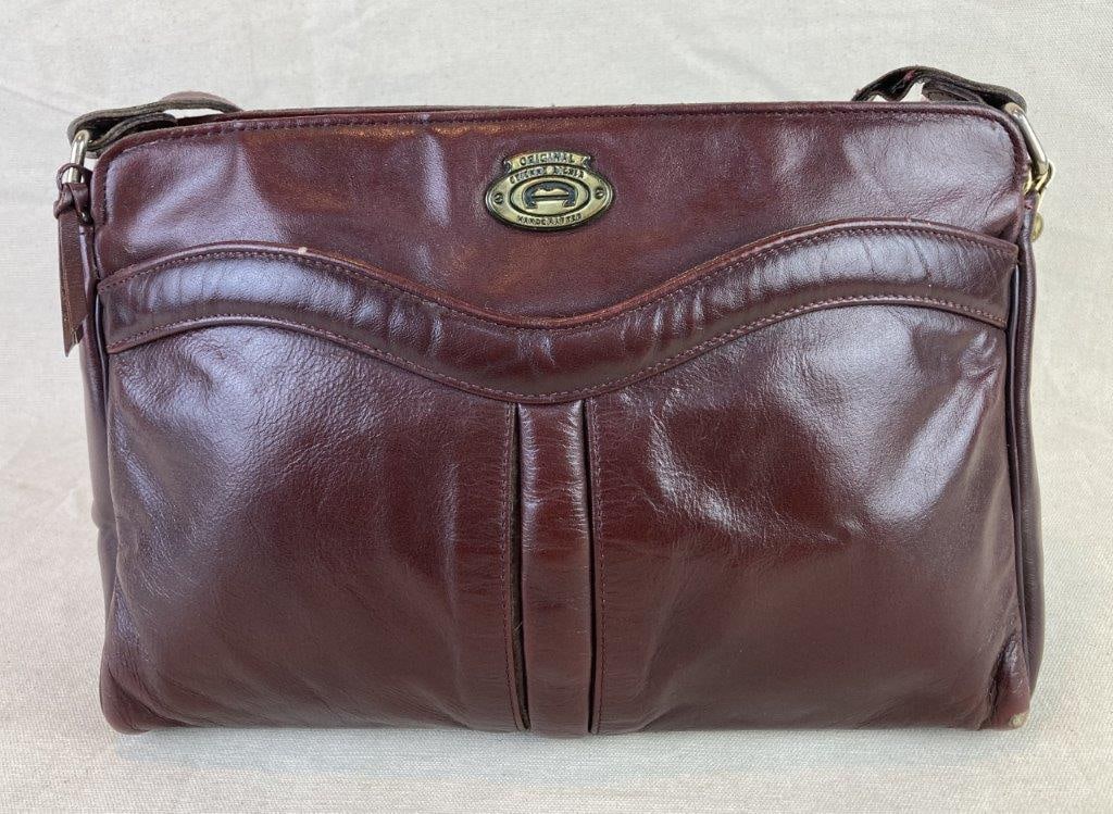 Vintage Etienne Aigner Oxblood Leather Shoulder Bag: Vintage Etienne Aigner shoulder bag crafted in rich oxblood leather with a classic zipper closure and fabric-lined interior. The front features a gold tone designer plaque identifying it as an iconic