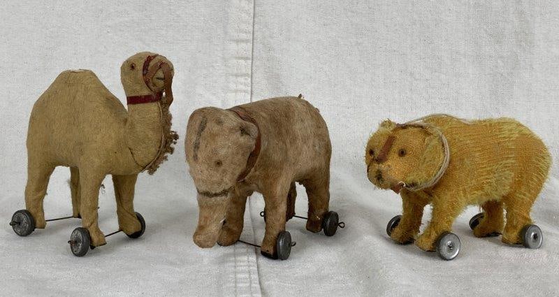Antique Animal Pull Toys: Charming set of three mohair animal pull toys including a camel, an elephant, and a yellow bear, all with glass eyes and wonderful early character. The camel features a Made in Germany sticker on the
