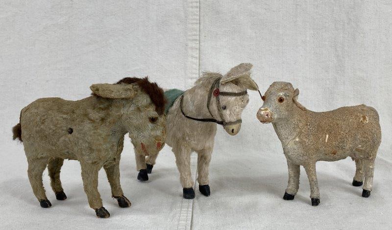 Three German Antique Mohair Animals: Group of three German antique mohair animals, including a wind-up donkey with brown glass eyes and a red painted nose and mouth, a putz cow with brown glass eyes, and a Steiff-style donkey featuring a