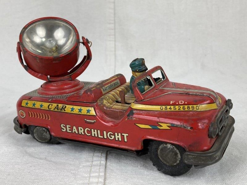 Vintage Tin Litho Searchlight Toy Car: Tin lithograph toy car featuring a rear-mounted searchlight and side lettering reading Car Searchlight F.D. Made by Excelo in Japan with an aged patina. Measures approximately 4 5/8" H x 2 7/8" W x 7 