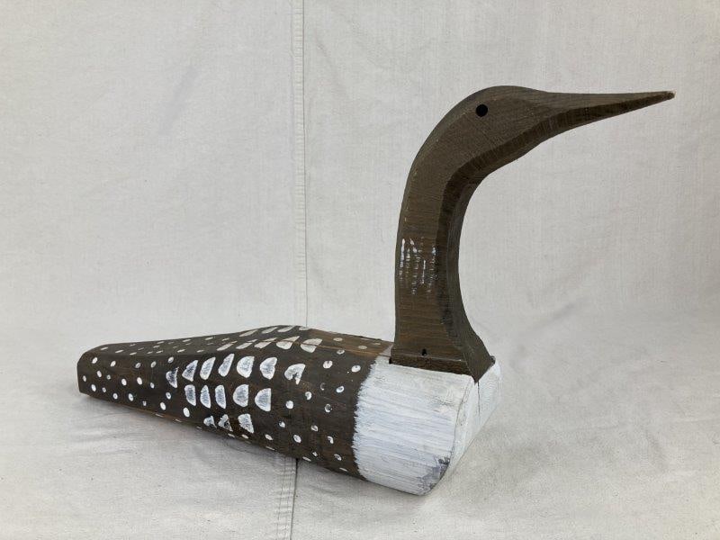 Country Goose Decoy: Country goose decoy made by The Decoy Shop, hand-carved with painted details and a worn patina, featuring a maker's stamp on the bottom. Measures approximately 12 7/8" H x 5" W x 22" D. Good condition