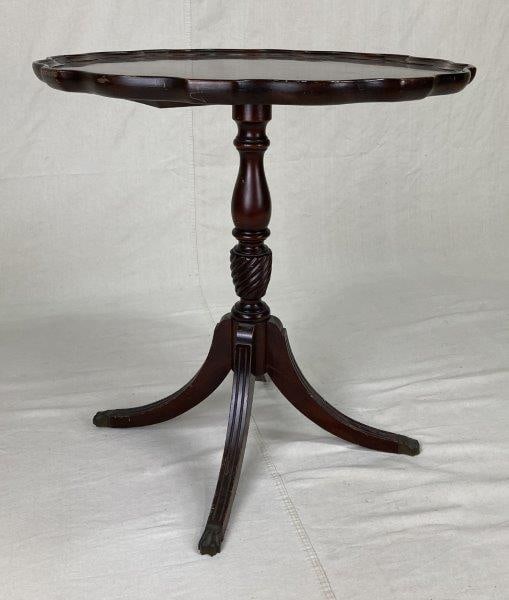Duncan Phyfe Style Table: A Duncan Phyfe-style table featuring a classic pie-crust round top and a turned pedestal base. The piece displays a warm, worn patina. Measures approximately 27 1/2" H x 26" W x 26 1/8" D. In good con