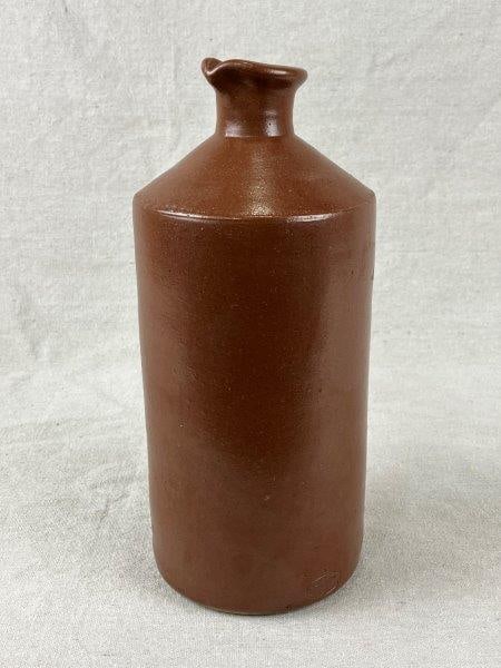 Lovatts Stoneware Pitcher: A Lovatts stoneware pitcher stamped with the maker's seal, finished in a rich sienna-brown glaze with classic utilitarian form. Measures approximately 10" H x 4 1/2" in diameter. In good condition.